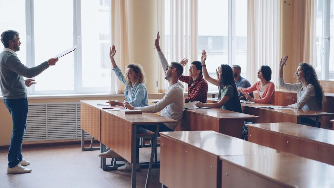 Teacher pointing at students with raised hands in a classroom