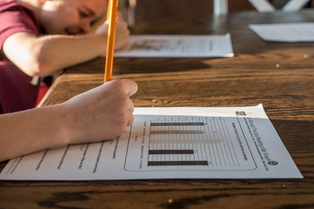 Close-up of a student writing answers on a graded worksheet